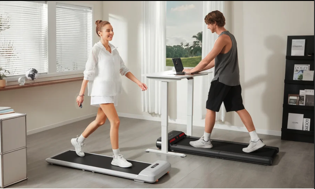 Two people walking on under-desk treadmills while working at standing desks